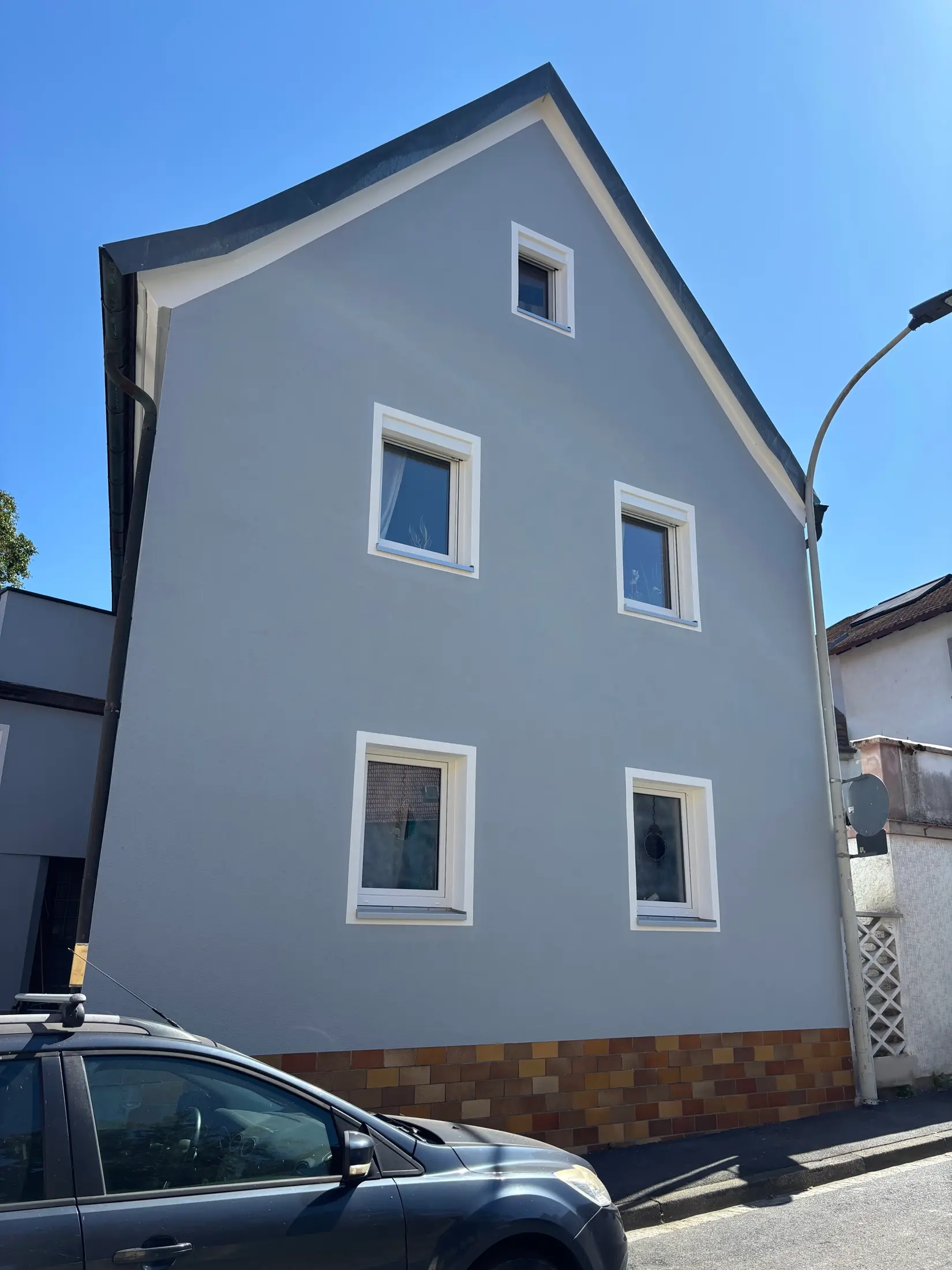 Frisch gestrichene Giebelfassade eines älteren Stadthauses mit weiß abgesetzten Fenstern und Sockel