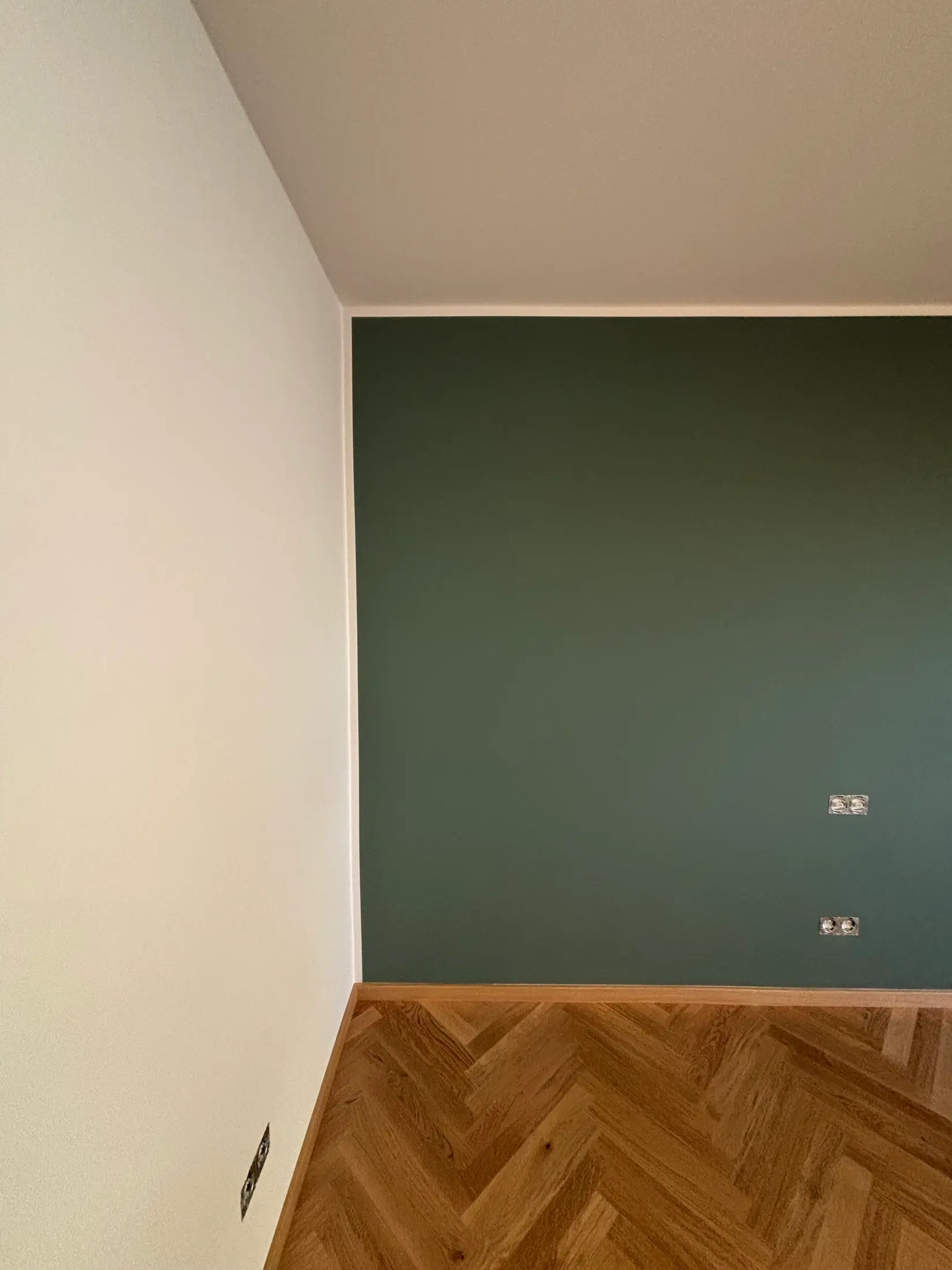 Dunkelgrüne Akzentwand mit sauberen Farbkanten und Fischgrätparkett